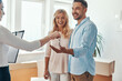 © gstockstudio - Young beautiful couple in casual wear smiling and embracing while receiving keys from new home