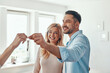 © gstockstudio - Young beautiful couple in casual wear smiling while receiving keys from new home