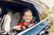 © gstockstudio - Happy little boy smiling and looking away while sitting on the back seat of the car