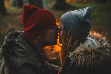 Wall Mural - Traveler couple camping in the forest and relaxing near campfire after a hard day. Concept of trekking, adventure and seasonal vacation.