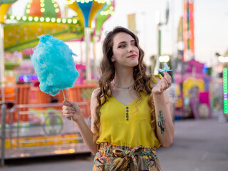 Wall Mural - Attractive Caucasian female posing with blue cotton candy at a carnival