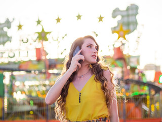 Wall Mural - Attractive Caucasian female posing talking on the phone at a carnival