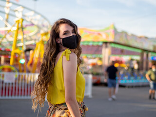 Wall Mural - Attractive Caucasian female in a protective mask posing at a carnival