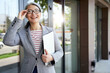 © Friends Stock - Cheerful middle-aged woman smiling and holding laptop outdoors