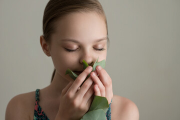 Wall Mural - Beautiful cheerful smiling girl with eucalyptus leaf branch breathes in the scent of leaf. Close up, selective focus.