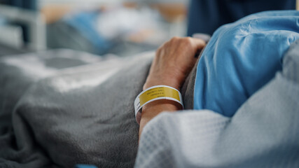 Wall Mural - Hospital Ward Bed: Recovering Old Patient Lying in the Hospital Bed Sleeping, Her Fragile Hands Resting on a Blanket, on it Information Wristband. Focus on the Hand.