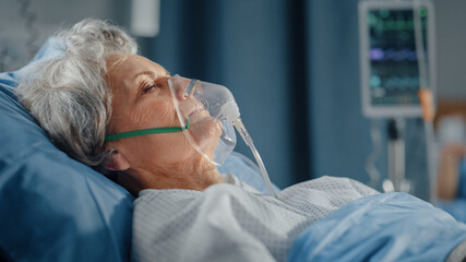 hospital ward: portrait of beautiful elderly woman wearing oxygen mask sleeping in bed, fully recove