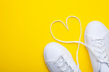 Pair Of Casual Shoes With Heart Shaped Laces On Yellow Background. Top View Of Stylish Sneakers On Color Background With Place For Text