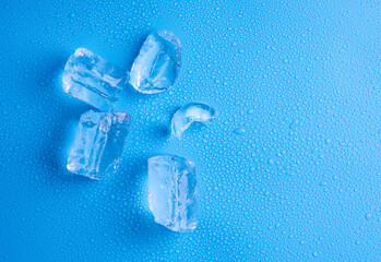 Sticker - Tube ice with water drops on a blue background, top view.