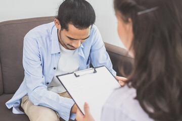 Wall Mural - Asian young asian man, male has mental symptoms which must have been therapy and stress, sitting on couch to consult to psychologist during session take notes to find out how to treat the therapist.