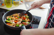 Woman cooking vegetables and shrimps on pan