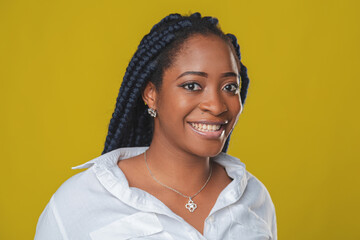 beautiful african american girl with pigtails hairstyle in a white shirt rejoices and smiles on a yellow background