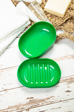 New Soap On A Green Plastic Soap Dish, On A White Wooden Background.