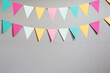 © annebel146 - Colorful party flags over cement concrete gray wall texture background, pastel birthday colored flags with copy space Holiday concept