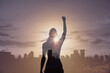 © kieferpix - Strong victorious woman with fist in the air facing the city. People power, and hero concept.