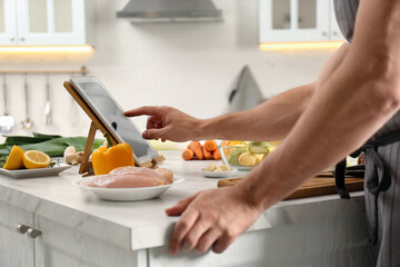 Poster - Man watching online cooking course via tablet in kitchen, closeup