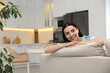© New Africa - Young woman relaxing on sofa at home, space for text