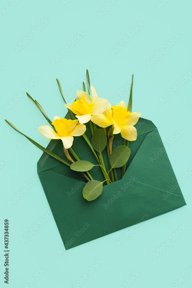 Envelope with beautiful daffodils on color background
