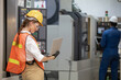 © nikomsolftwaer - Factory worker is programming a CNC milling machine with a tablet computer. engineering and worker woman in safety hard hat and reflective cloth using lathe machine inside the factory.