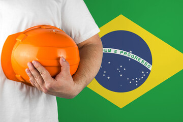 Worker with Brazil flag on background for working on labor day. Construction concept.