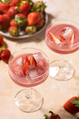 Two glasses with red strawberry dessert with ice cubes and crashed ice and strawberry slices, close up