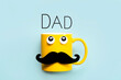 Happy Father's Day.Yellow mug with mustache and funny eyes looking up with the text Dad