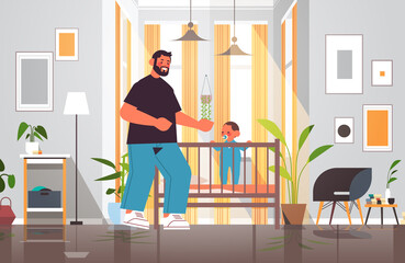 Wall Mural - young father playing with little son in crib fatherhood parenting concept dad spending time with his kid at home