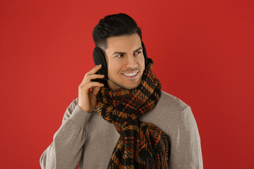 Sticker - Man wearing stylish earmuffs and scarf on red background