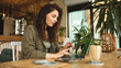 © Bogdan - Beautiful young girl working at a coffee shop with a laptop.female  holding a phone and credit card making online order, online shopping, online trading