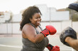 African curvy girl and personal trainer doing boxing workout session outdoor with her personal trainer - Focus on face