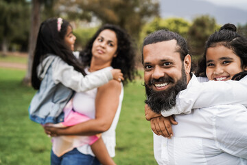 Wall Mural - happy indian family having fun outdoor at city park - main focus on father face