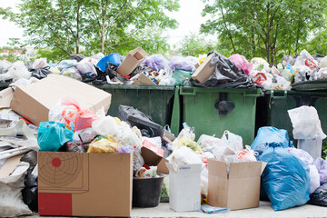 Overloaded dumpster, full garbage container, household garbage bin, trash can, heap of unsorted rubbish: plastic bags, food, paper, glass bottles, metal scrap, pile of refuse, litter, waste management