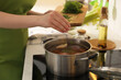 © New Africa - Woman putting dill into pot to make bouillon in kitchen, closeup. Homemade recipe