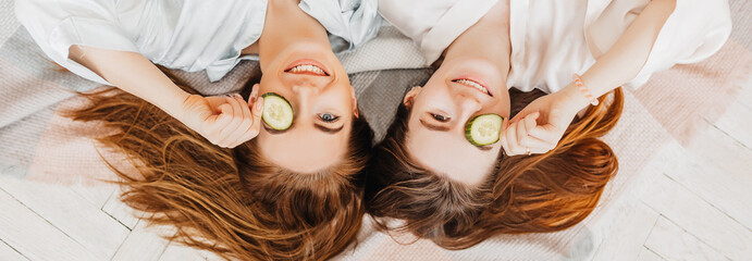 Wall Mural - two girls make homemade face and hair beauty masks. cucumbers for the freshness of the skin around t