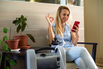 girl using oxygen breathing machine at home and talking by video with friend online. breathing devic