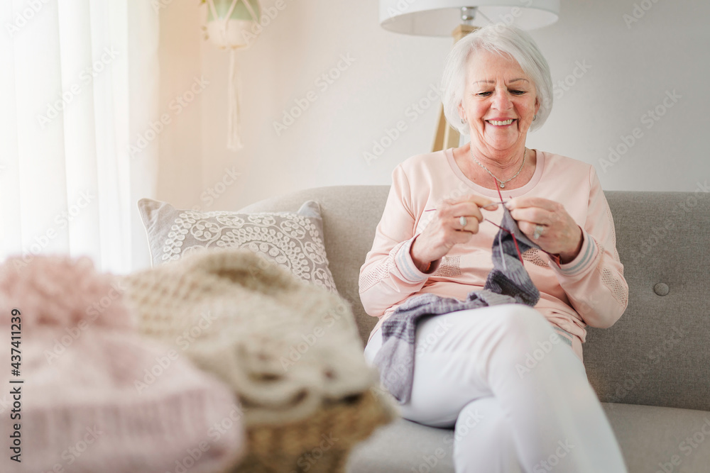 Senior knitting on her sofa at home Stock Photo | Adobe Stock
