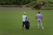 A golfer and his caddy look down the fairway during a tournament. 