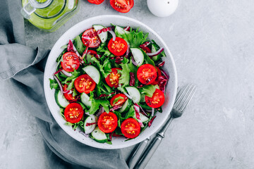 Wall Mural - Green salad bowl with tomatoes, cucumbers, red onions, radicchio and fresh lettuce.