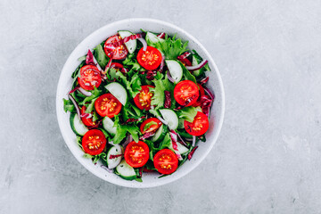 Wall Mural - Green salad bowl with tomatoes, cucumbers, red onions, radicchio and fresh lettuce.