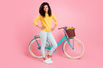 Wall Mural - Full length body size view of pretty content cheerful girl with bike hands on hips isolated over pastel pink color background