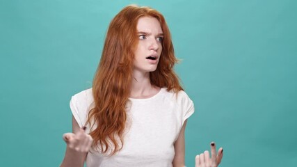 Canvas Print - Confused ginger woman in panic over turquoise background