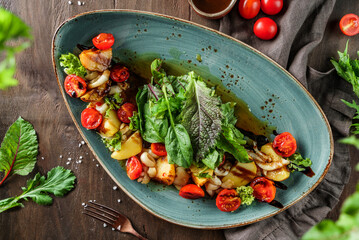 Wall Mural - Baked potatoes with salad and tomatoes in plate on wooden background. Healthy vegan food, clean eating, dieting, top view