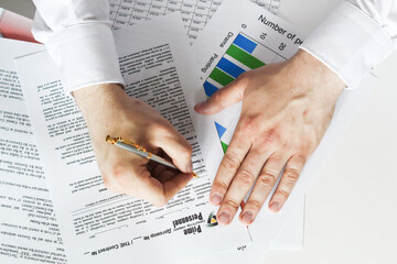 A businessman sitting at an office desk signs a contract with a shallow emphasis on signing. business and finance