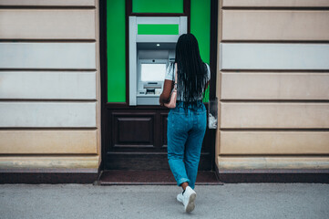 Wall Mural - Attractive african american woman using credit card and withdrawing cash at the ATM