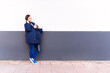 © Patricia - young adult woman talking on the smartphone carrying her baby leaning on a gray and white wall with a serious gesture receiving bad news