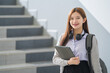 © EduLife Photos - Portrait of a young Asian woman student in uniform holding tablet in smart and happy pose in university or college classroom. Youth girl student and tutoring education with technology learning concept