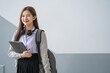 © EduLife Photos - Portrait of a young Asian woman student in uniform holding tablet in smart and happy pose in university or college classroom. Youth girl student and tutoring education with technology learning concept