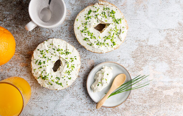 Wall Mural - Breakfast table with bagels fresh cheese. Bagels with fresh cheese and herbs on a breakfast table , with fresh orange juice and coffee on the side.