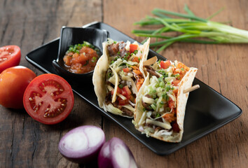 Slow cooked short ribs on tortillas with a spring onion tomato salsa isolated on wooden table