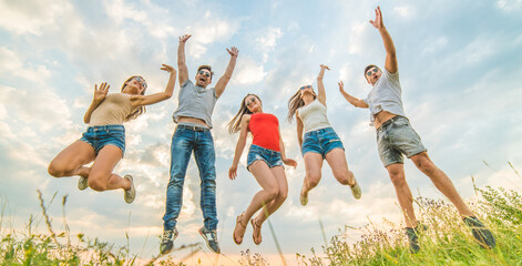 The happy friends jumping on the background of the clouds